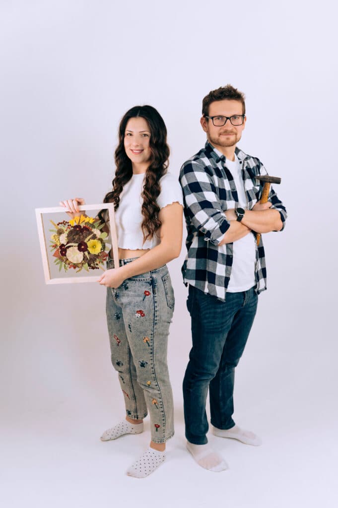 Armína a Honza ve studiu – ona drží rám s lisovanými květinami, on drží kladivo